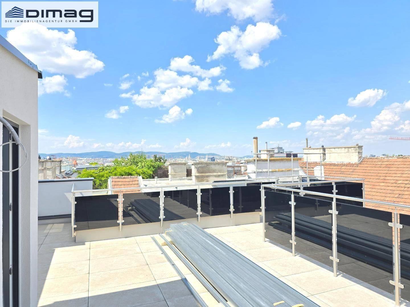 Große Dachterrasse im Rohbau mit Stadtblick und viel Sonnenlicht.