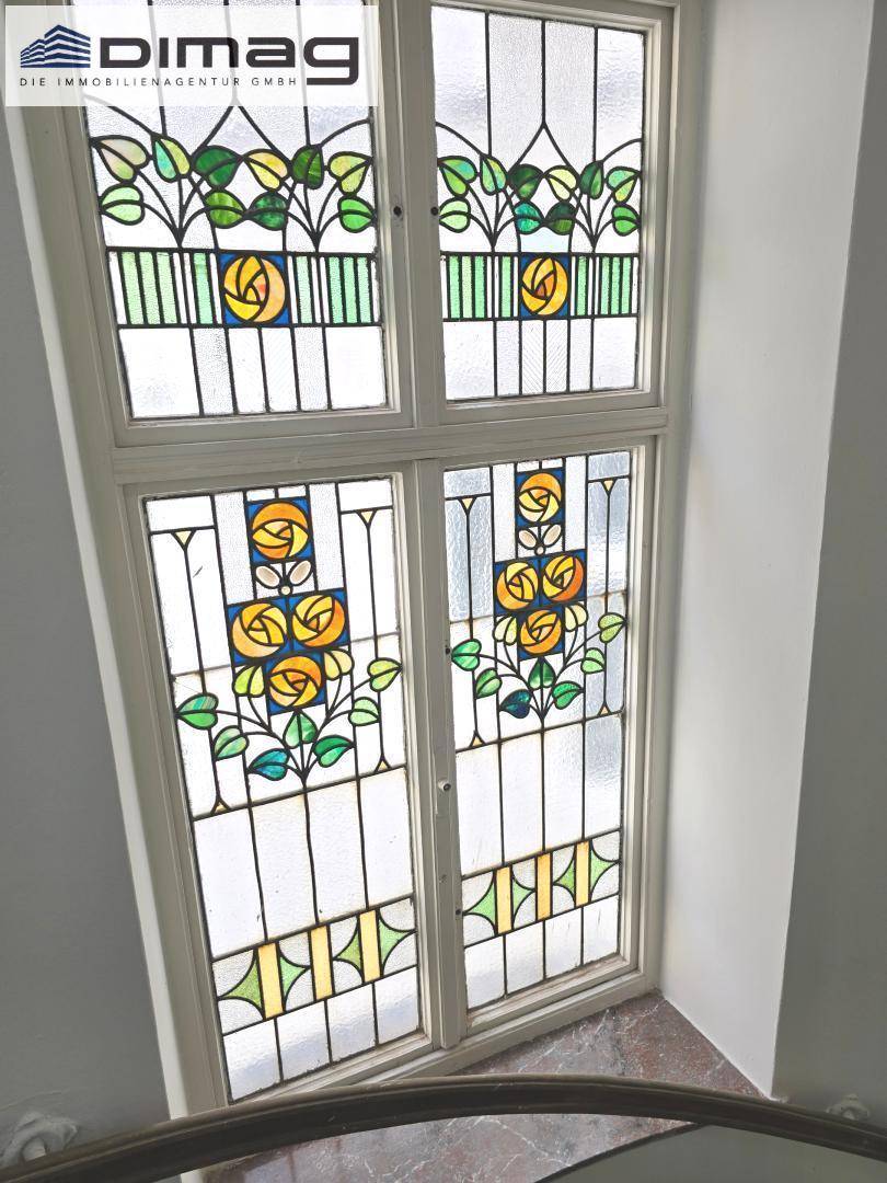 Historisches Treppenhausfenster mit farbenfrohen Jugendstil-Glasmalereien.