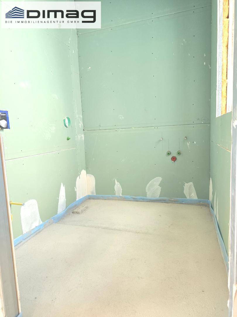Rohbau eines Badezimmers mit grünen Trockenbauwänden und Installationsvorbereitungen.