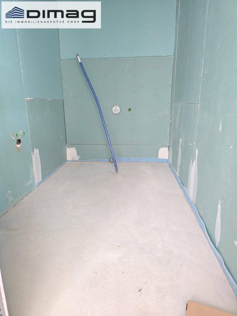 Rohbau eines Badezimmers mit vorbereiteten Anschlüssen für Dusche oder Badewanne.