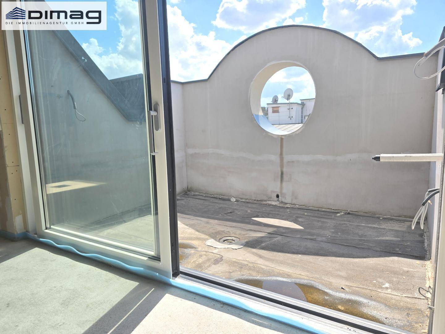 Dachterrasse im Rohbau mit runder Öffnung und Blick auf die Umgebung.