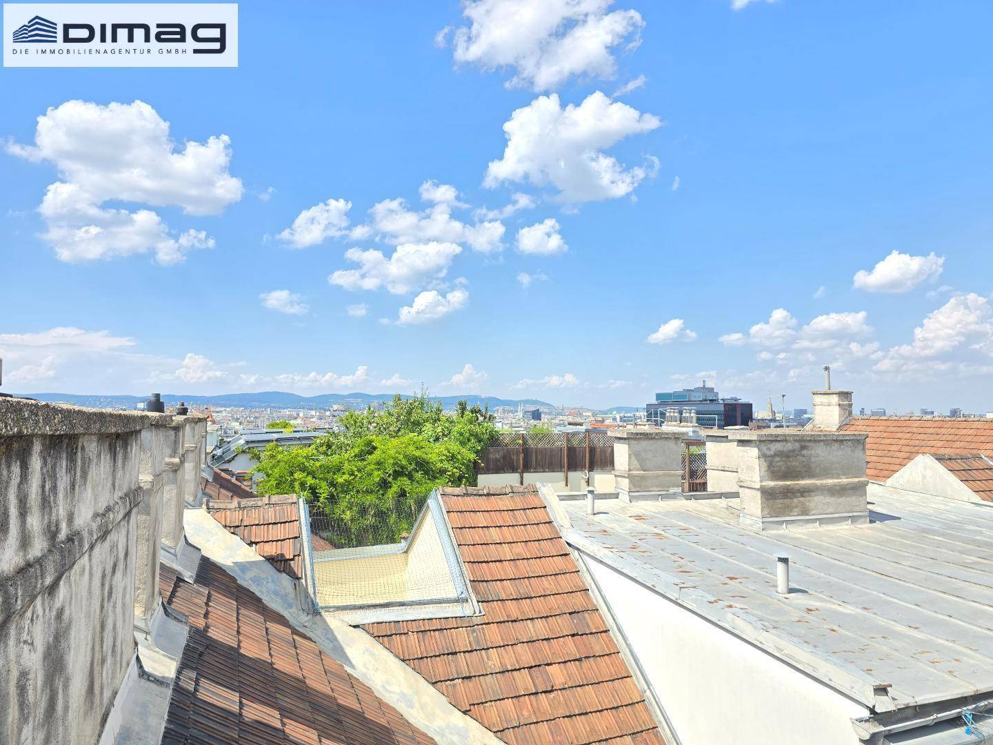Weitläufiger Blick über die Dächer der Stadt unter blauem Himmel.