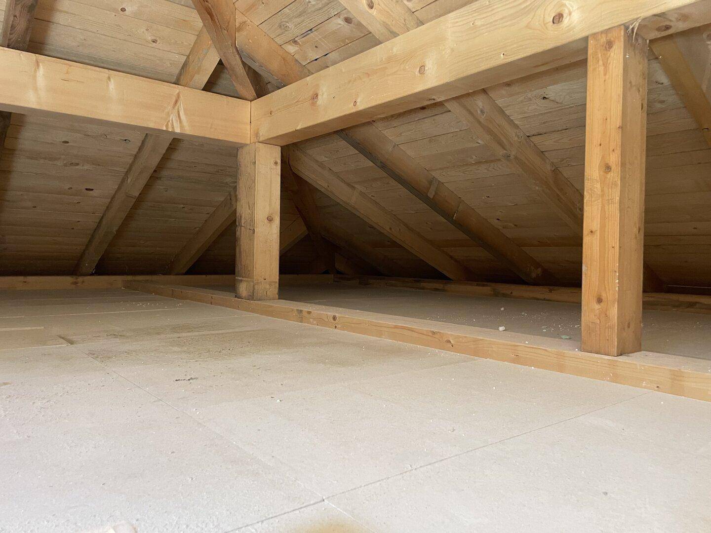 Geräumiger Dachboden mit freiliegenden Holzbalken und Holzkonstruktion, bereit für Ausbau oder Lagerung.