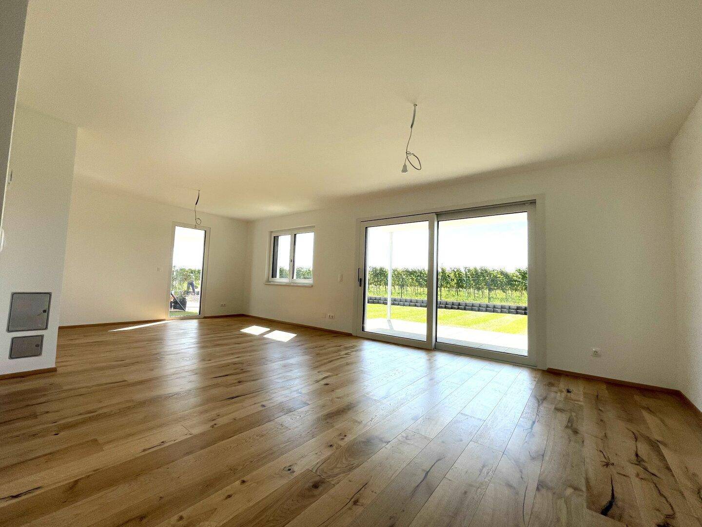 Geräumiges Wohnzimmer mit Holzboden, großen Schiebetüren und direktem Blick auf den Weinberg.