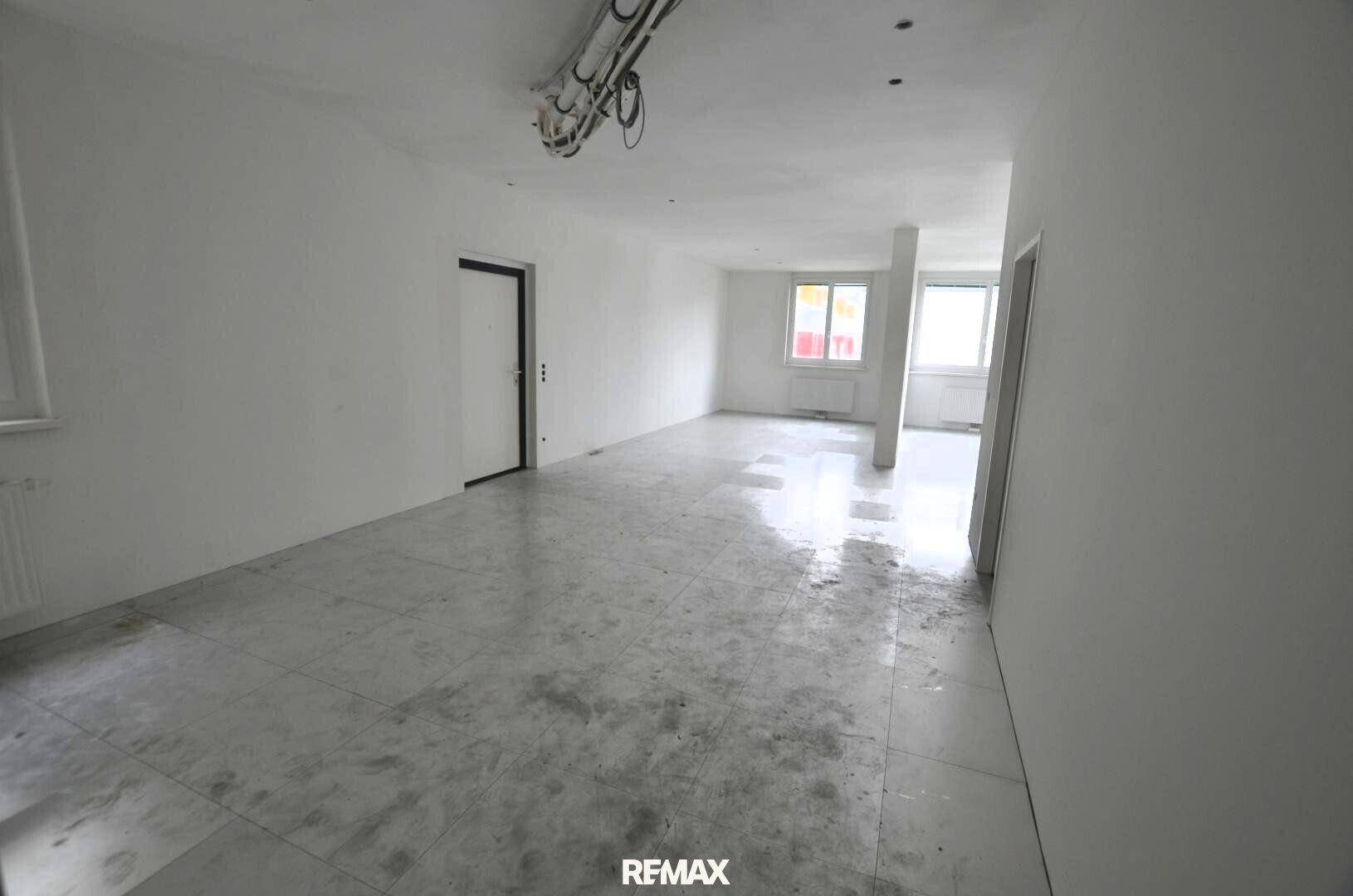 Leerer Raum mit weißen Wänden und hellen Fliesen, bereit für den Ausbau oder die Renovierung.