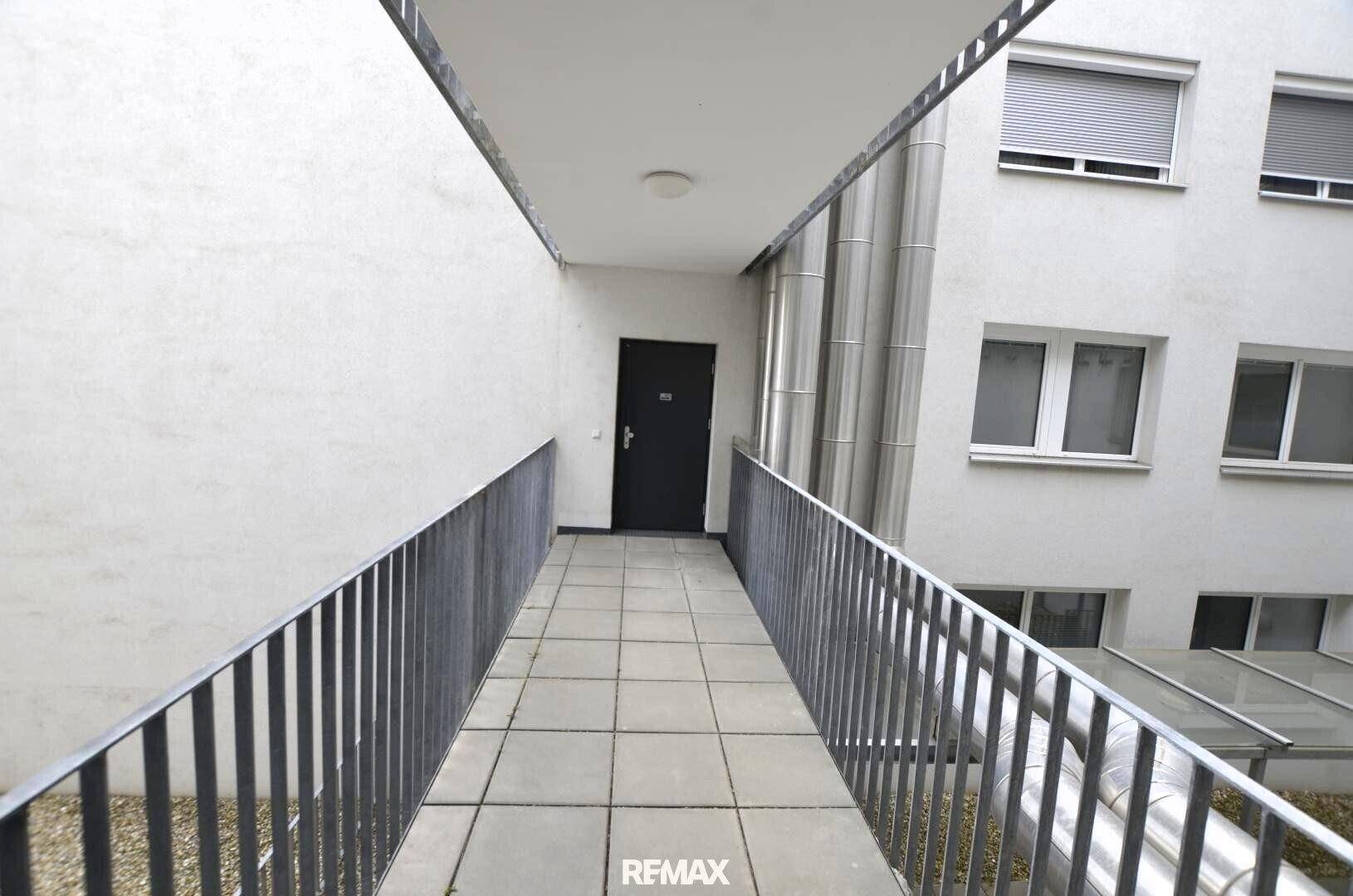 Außenbereich mit Rampe und Geländer, führt zu einem Eingang in einem modernen Gebäude.