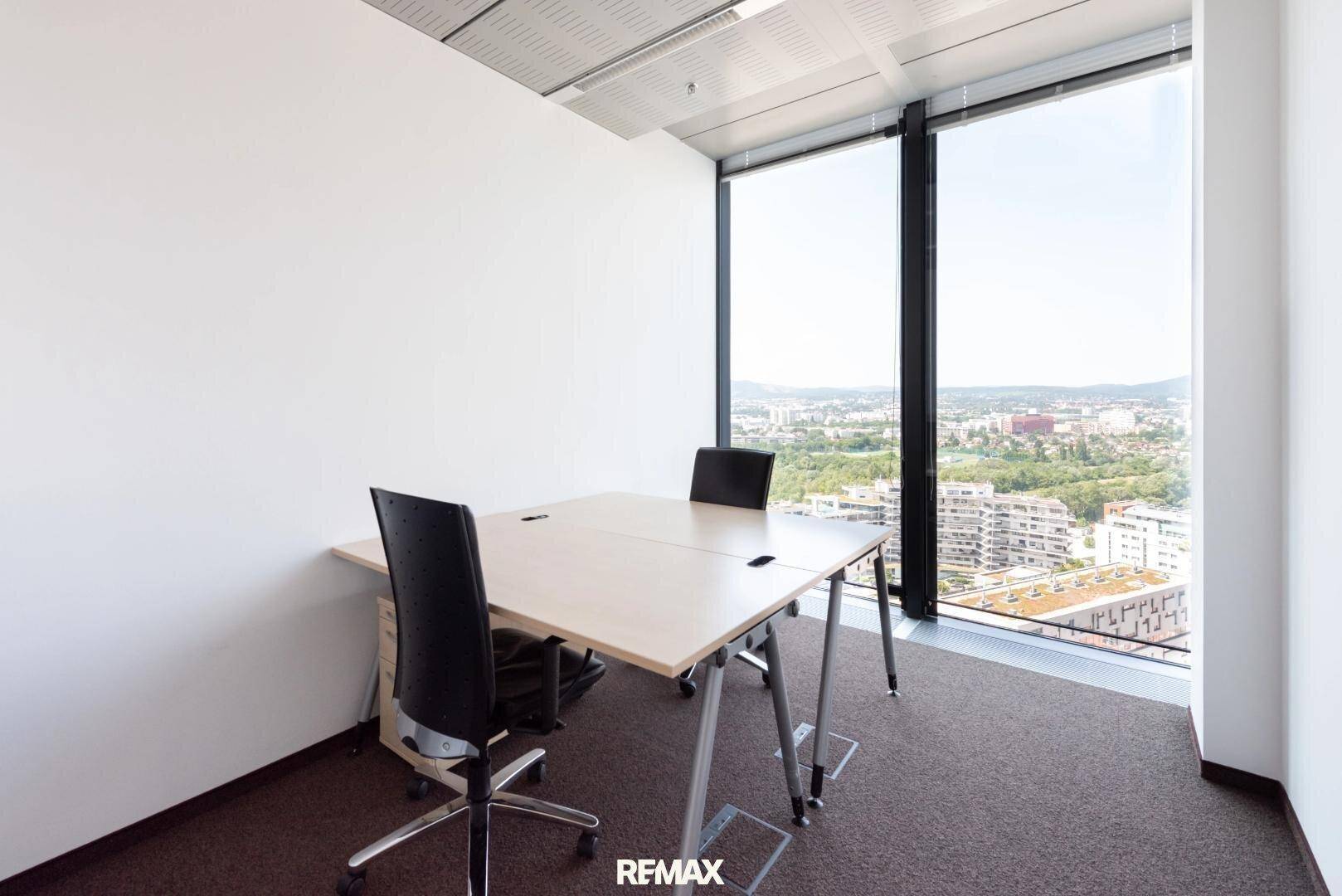 Kompaktes Büro mit zwei Arbeitsplätzen, Teppichboden und weitem Blick über die Stadt.