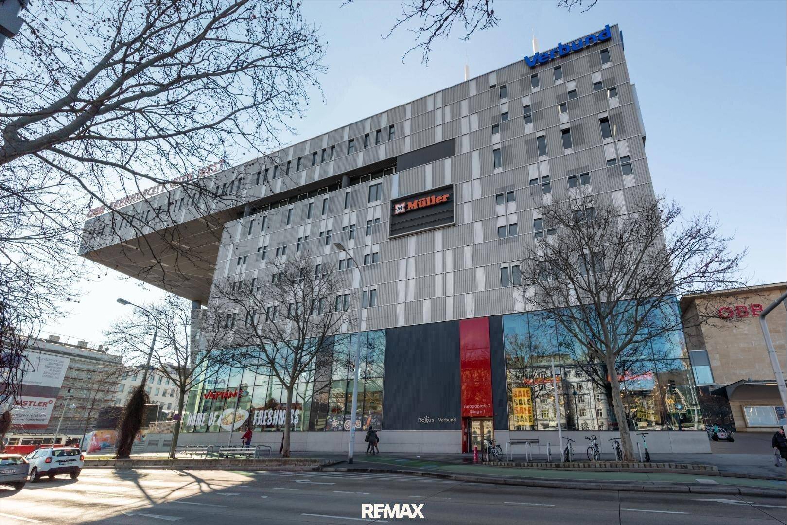 Moderne Architektur eines Geschäftsgebäudes mit markanter Glasfassade und auskragendem Obergeschoss.