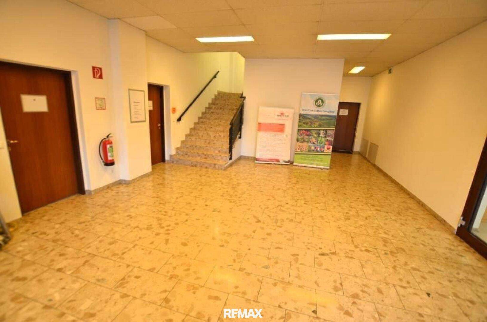 Geräumiger Eingangsbereich mit gefliestem Boden, einer Treppe und mehreren Türen zu angrenzenden Räumen.