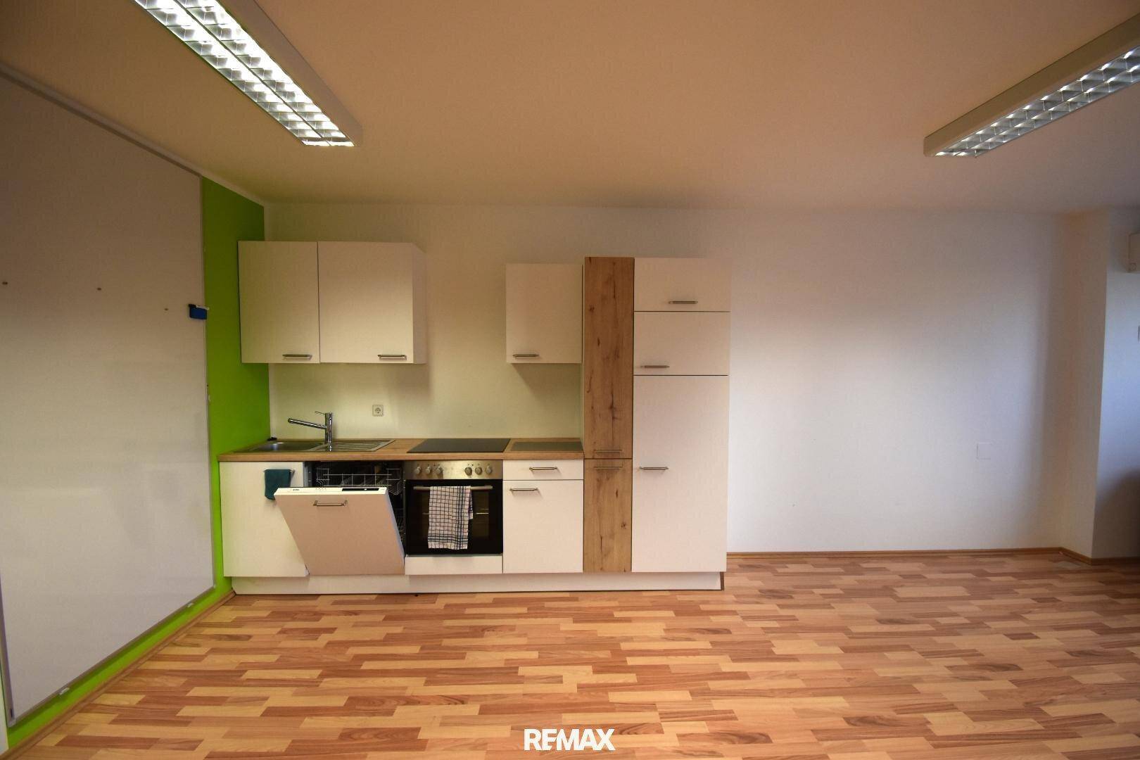 Moderne Küchenzeile in Weiß mit integrierten Geräten und grünem Akzent an der Wand.