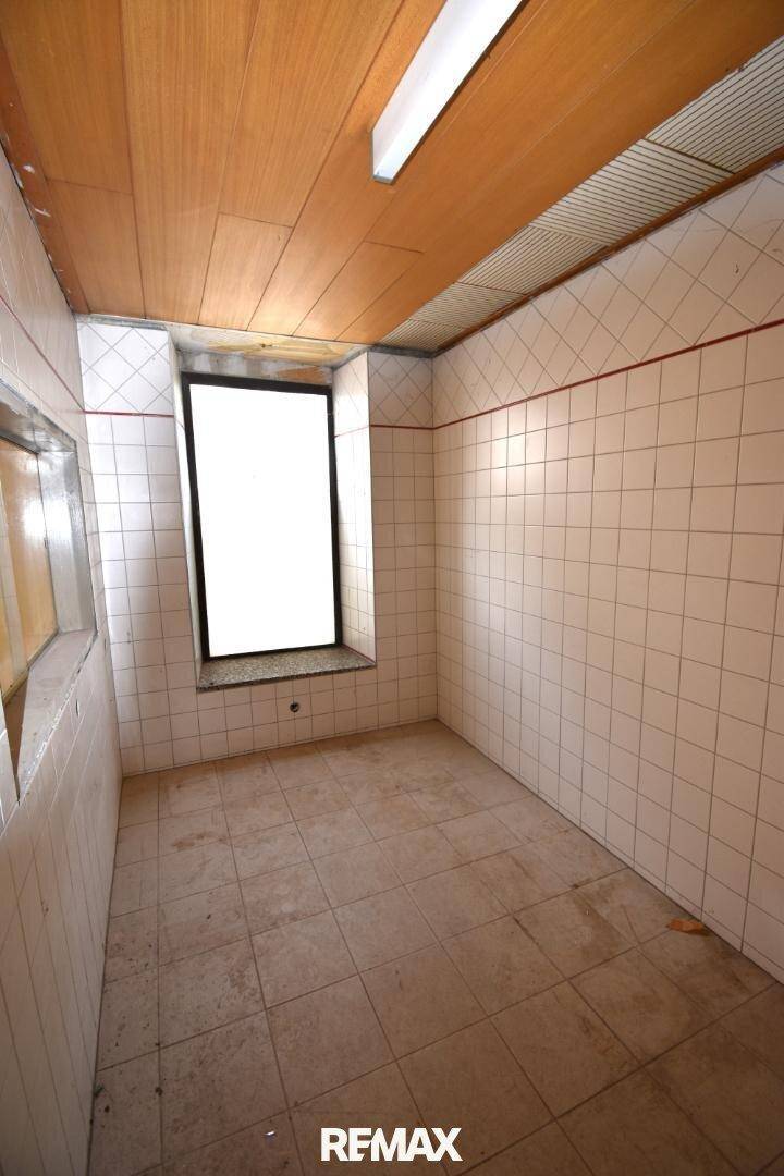 Gefliester Raum mit Holzwandverkleidung an der Decke und einem kleinen Fenster.