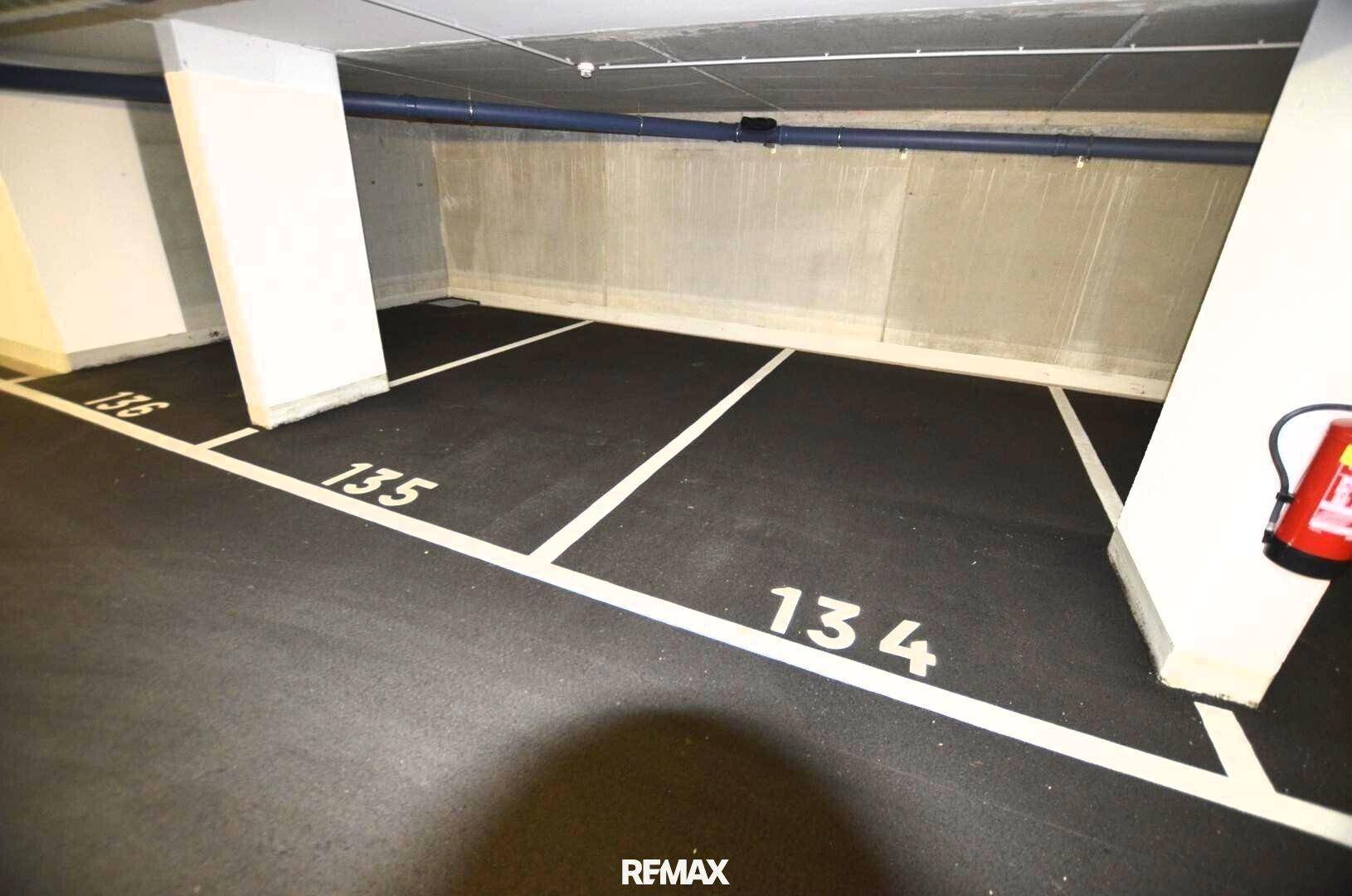 Mehrere nummerierte Tiefgaragenstellplätze mit einem Feuerlöscher für die Sicherheit.