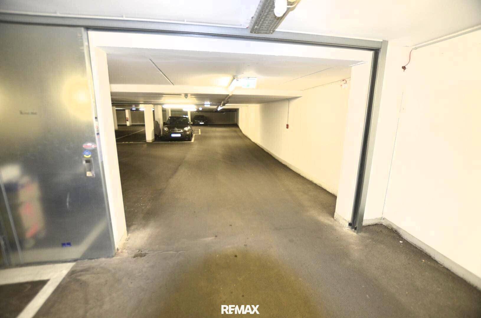 Zufahrt zu den Tiefgaragenstellplätzen mit einer breiten Schiebetür und guter Beleuchtung.