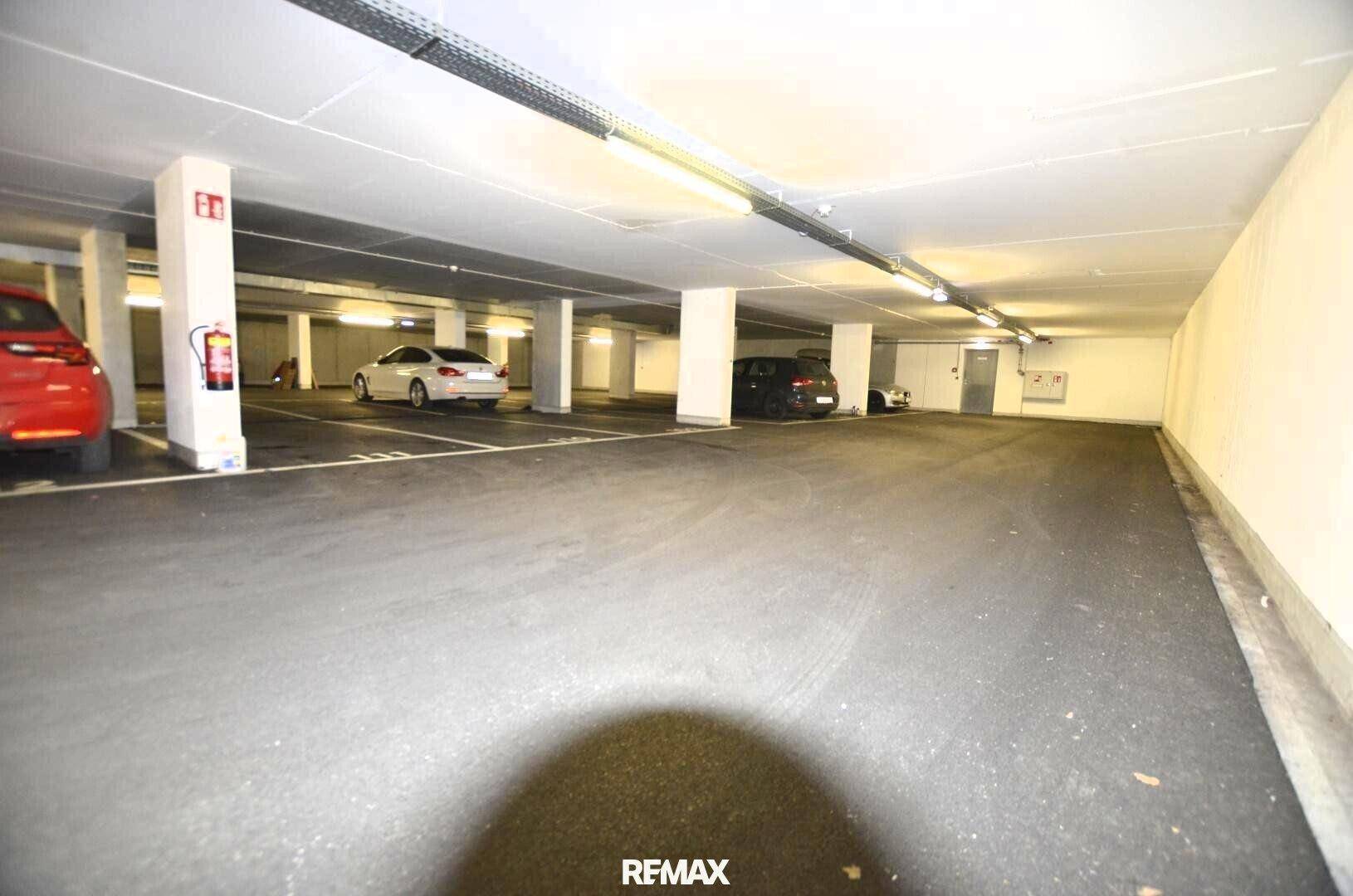 Weitläufige Tiefgarage mit zahlreichen Stellplätzen, guter Beleuchtung und Sicherheitsausrüstung.