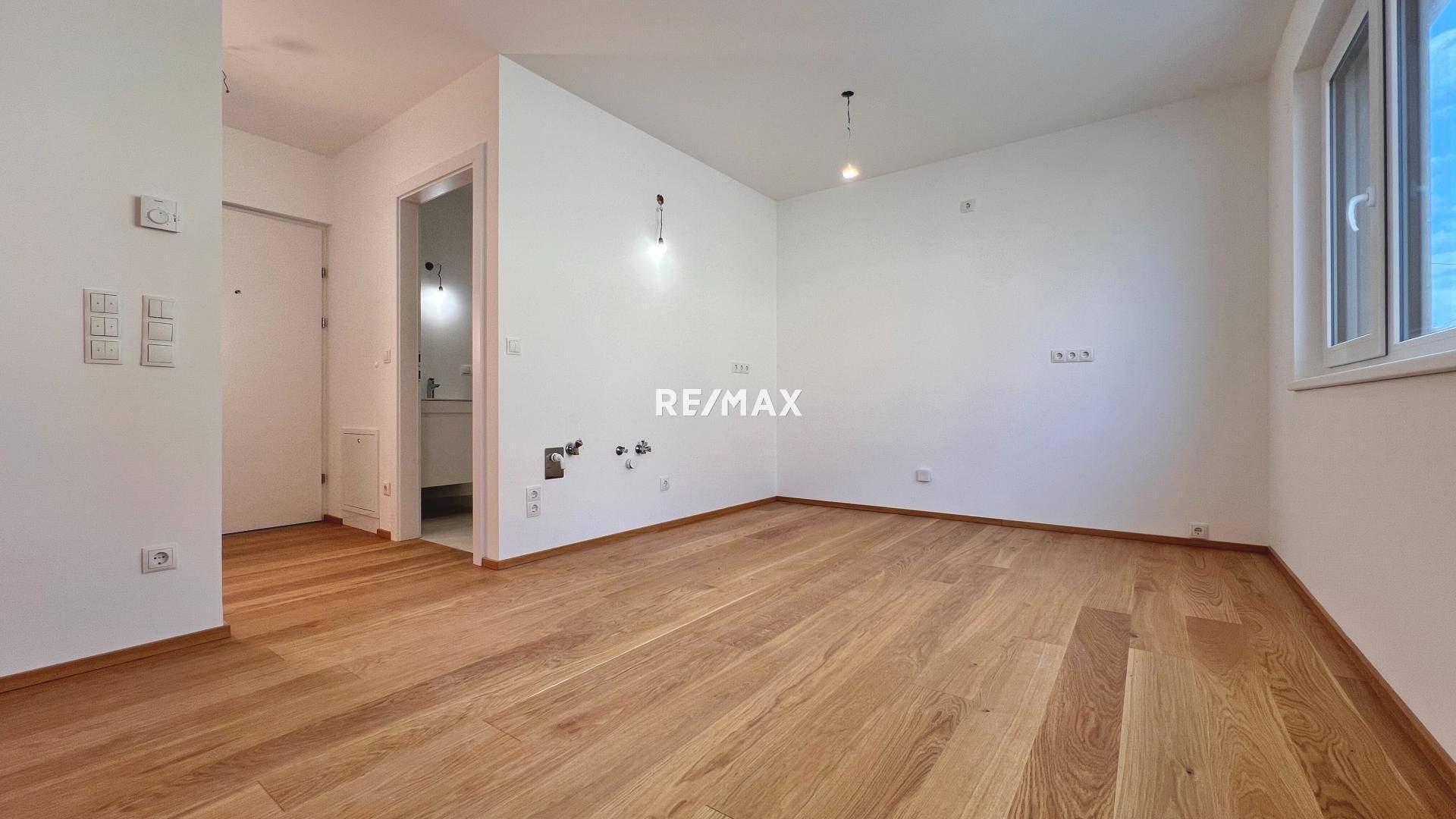 Geräumiger, heller Wohnraum mit Holzboden und weiß gestrichenen Wänden, bereit für individuelle Gestaltung.