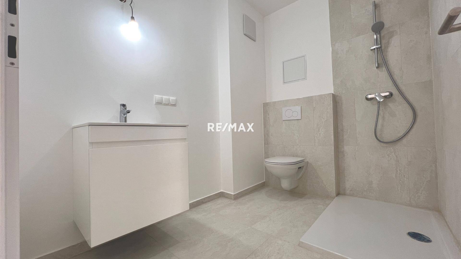 Modernes Badezimmer mit Dusche, wandhängendem WC und schwebendem Waschtisch in hellen, neutralen Farbtönen.