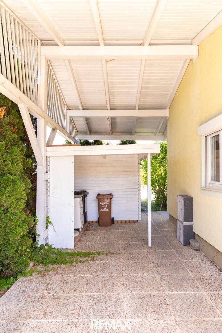 Überdachter Außenbereich neben dem Haus, ideal für Abfallbehälter und Lagerung.