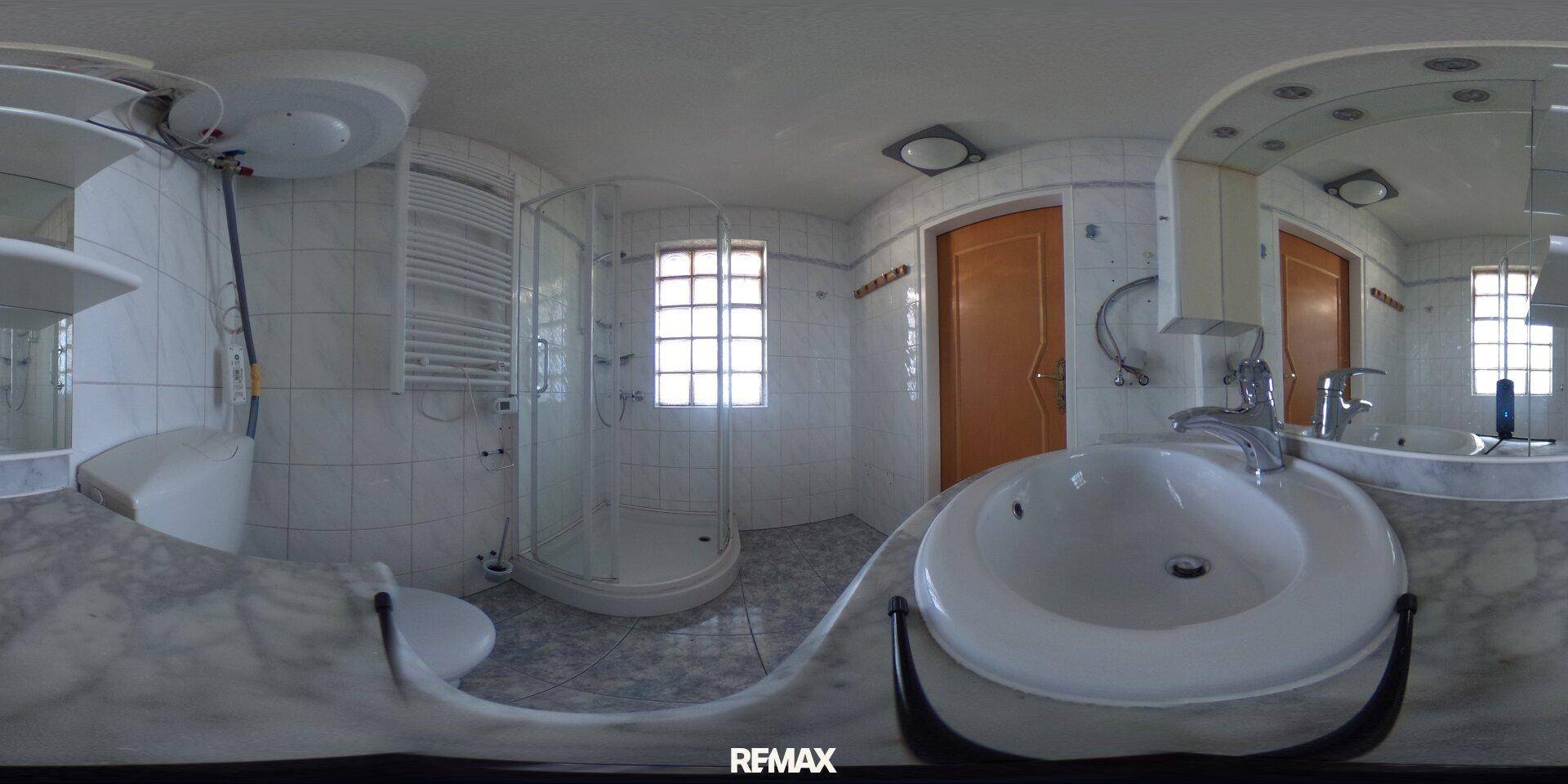 Panoramaansicht eines Badezimmers mit weißen Fliesen, Waschbecken, Toilette und Duschkabine.