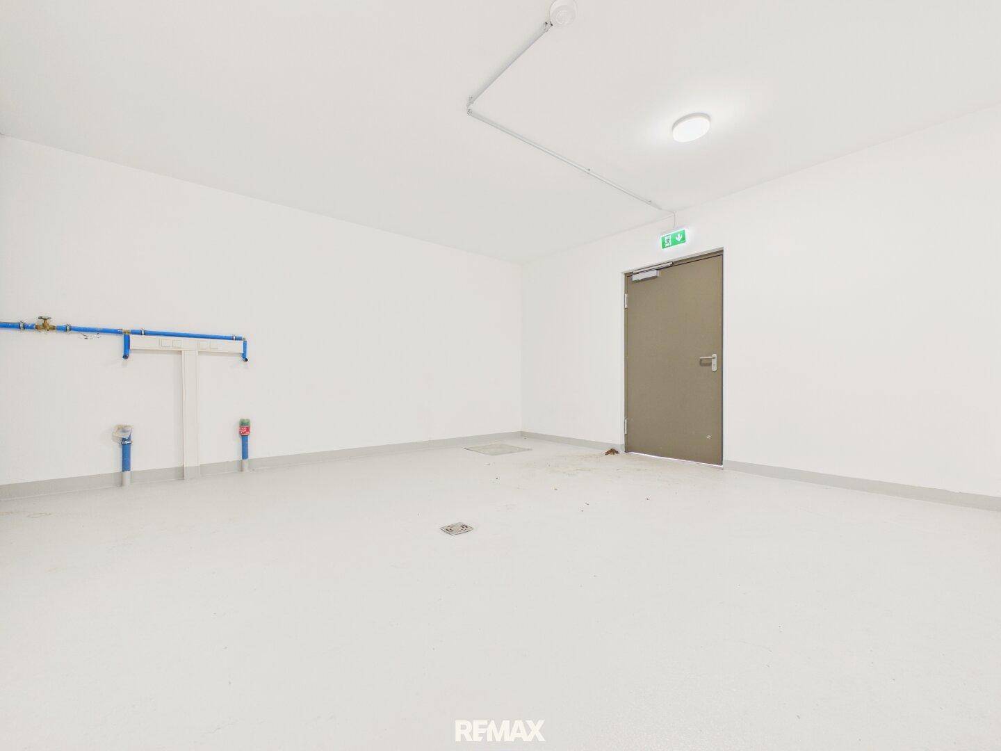 Geräumiger Hauswirtschaftsraum mit hellen Wänden und sichtbaren Installationen, ideal als Abstellraum.
