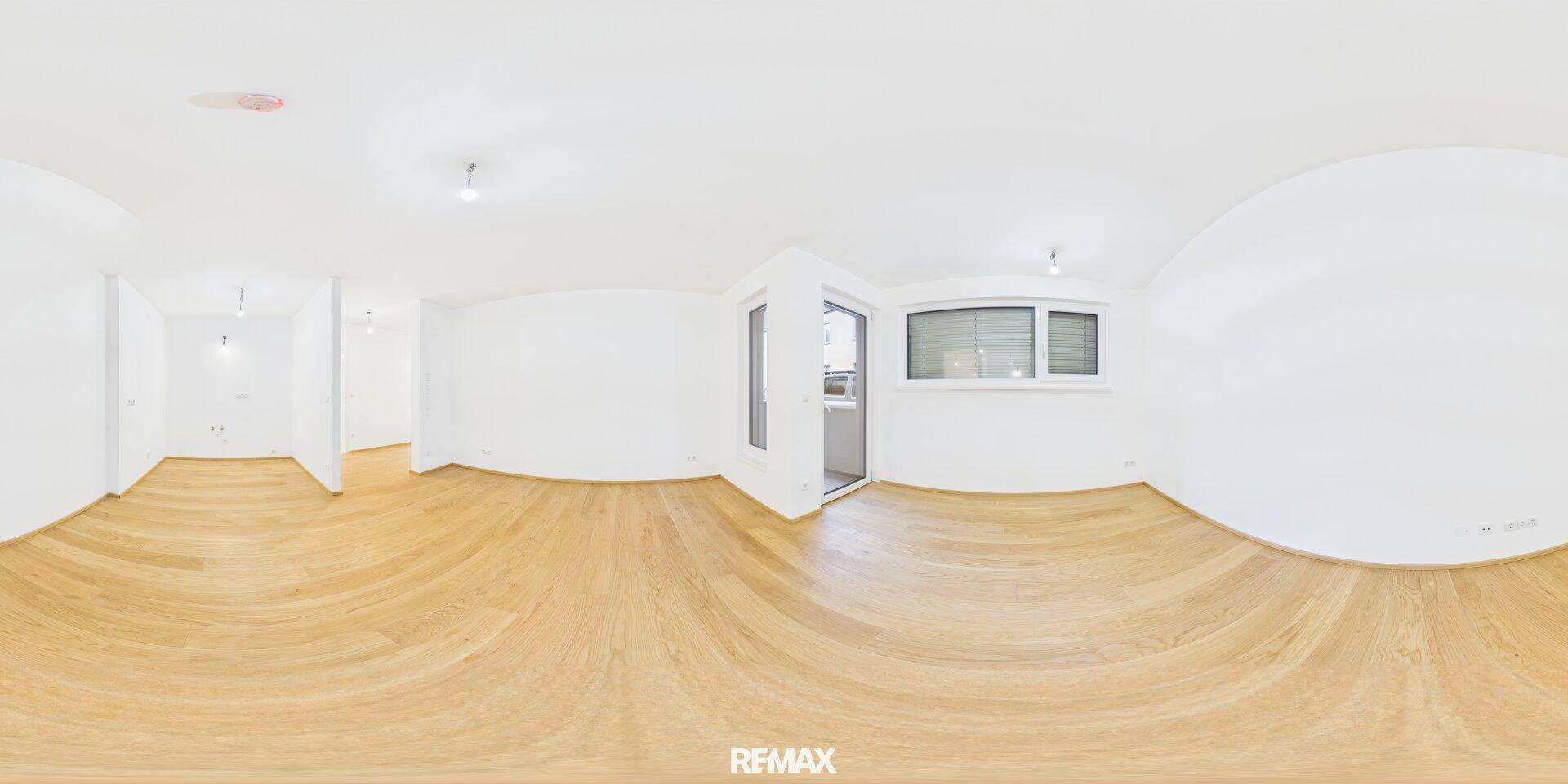 Helles und geräumiges Wohnzimmer mit hellem Holzparkettboden und großen Fenstern, ideal für Familien.