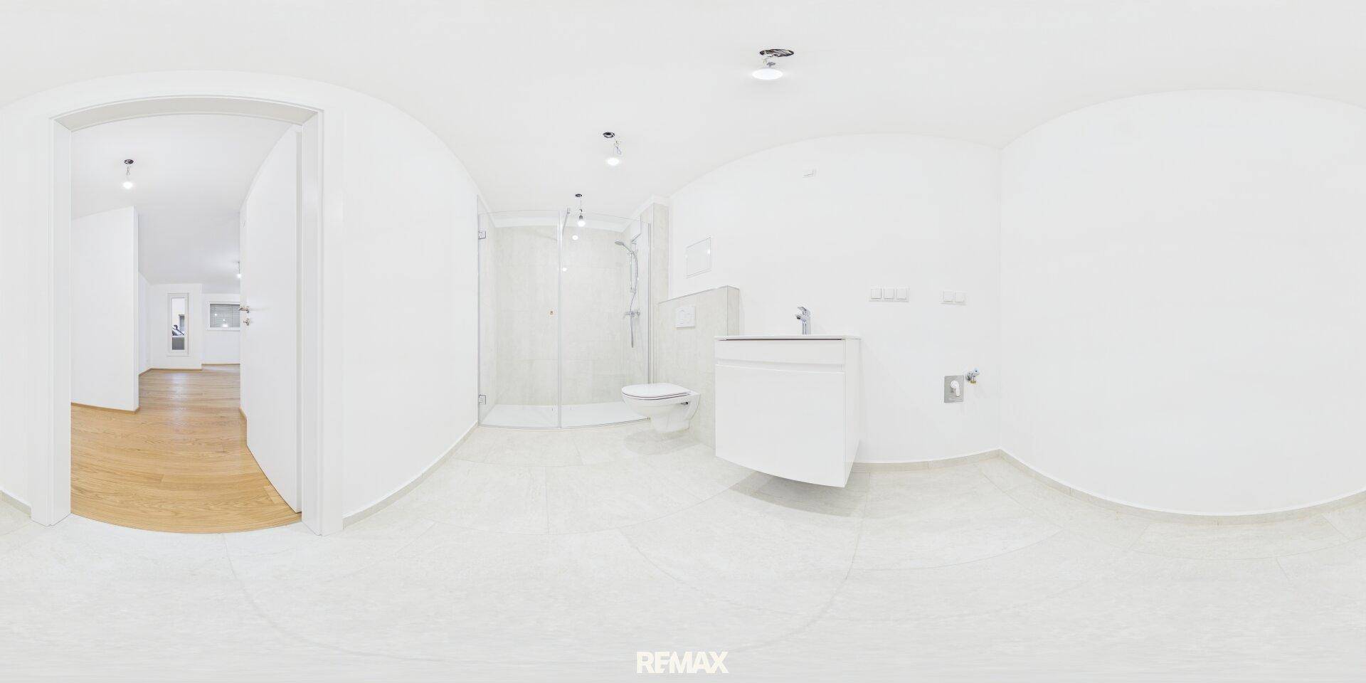 Panoramablick auf ein modernes Badezimmer mit ebenerdiger Dusche und Waschtisch.