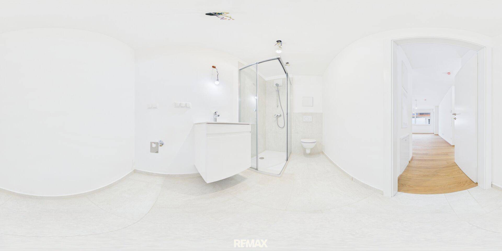 Modernes Badezimmer mit Duschkabine, Waschbecken und Toilette in hellen Farben.