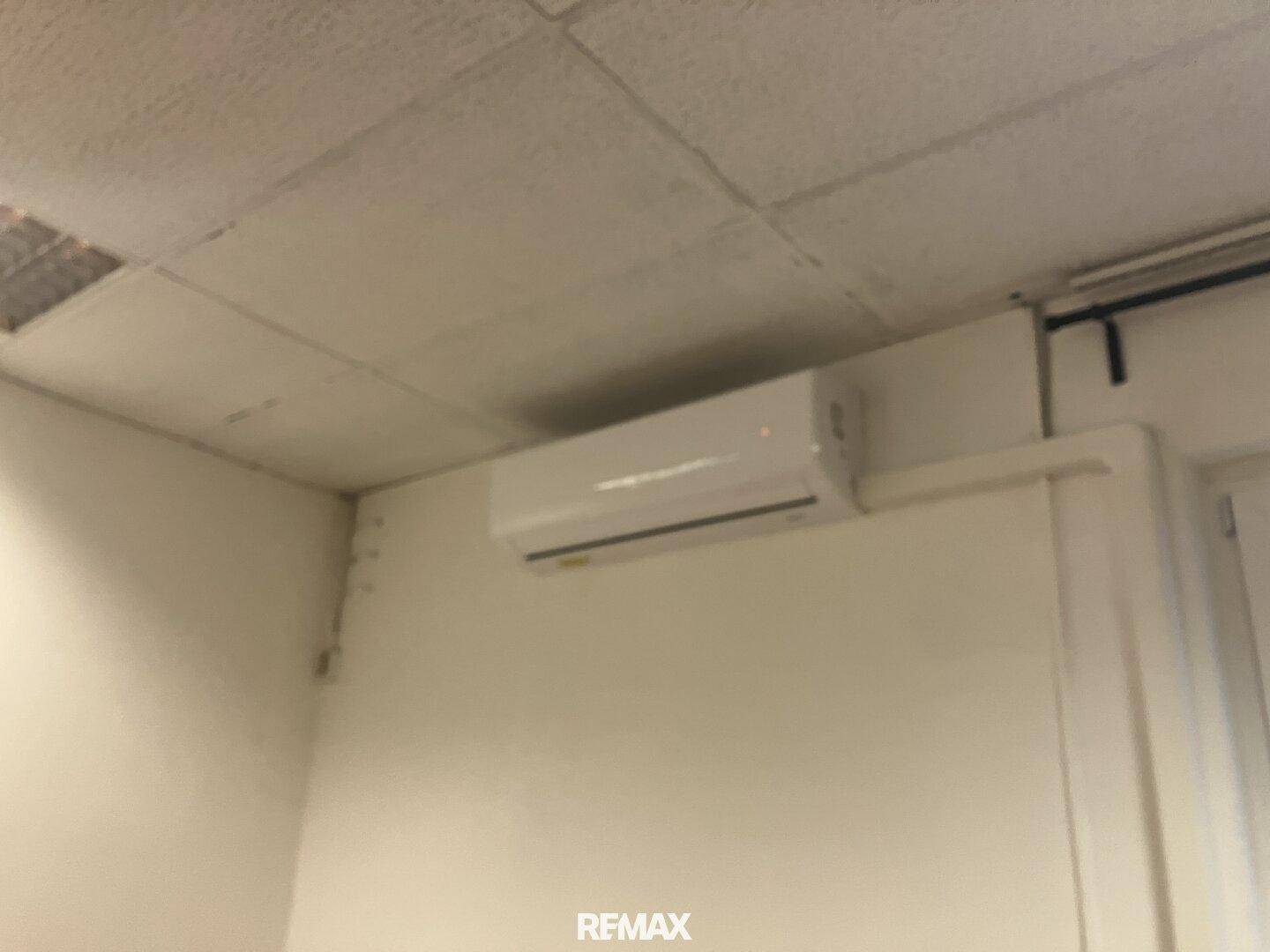 Wandmontierte Klimaanlage unter einer Rasterdecke in einem Innenraum.