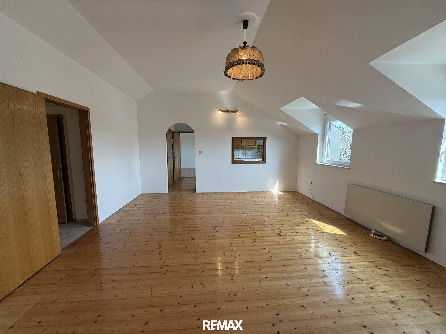 Helles, geräumiges Zimmer im Dachgeschoss mit Holzdielenboden und schrägen Wänden.