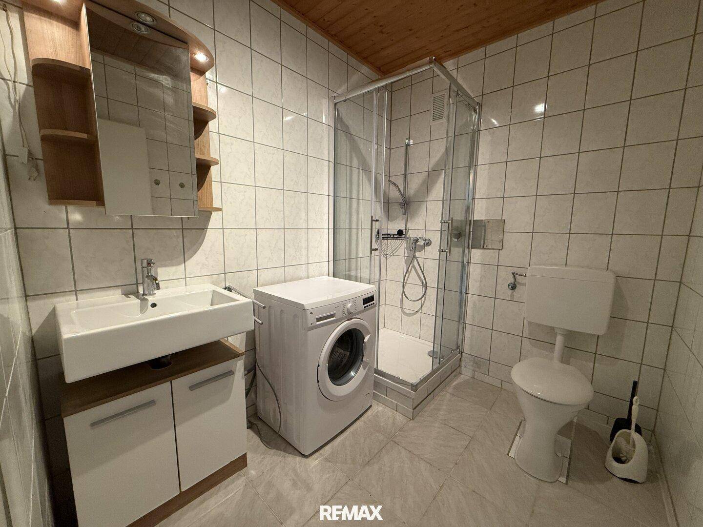 Modernes Badezimmer mit Duschkabine, Waschbecken und WC, ausgestattet mit weißen Fliesen.