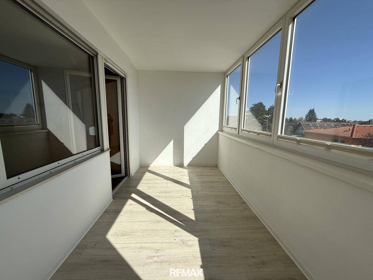 Helle Loggia mit großen Fenstern und viel Tageslicht, bietet einen weiten Blick auf die Umgebung.