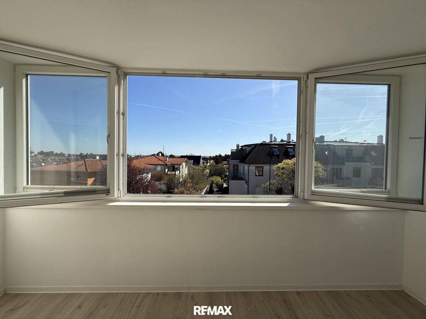 Heller Raum mit großem Fenster und weitem Blick über die umliegende Wohngegend.
