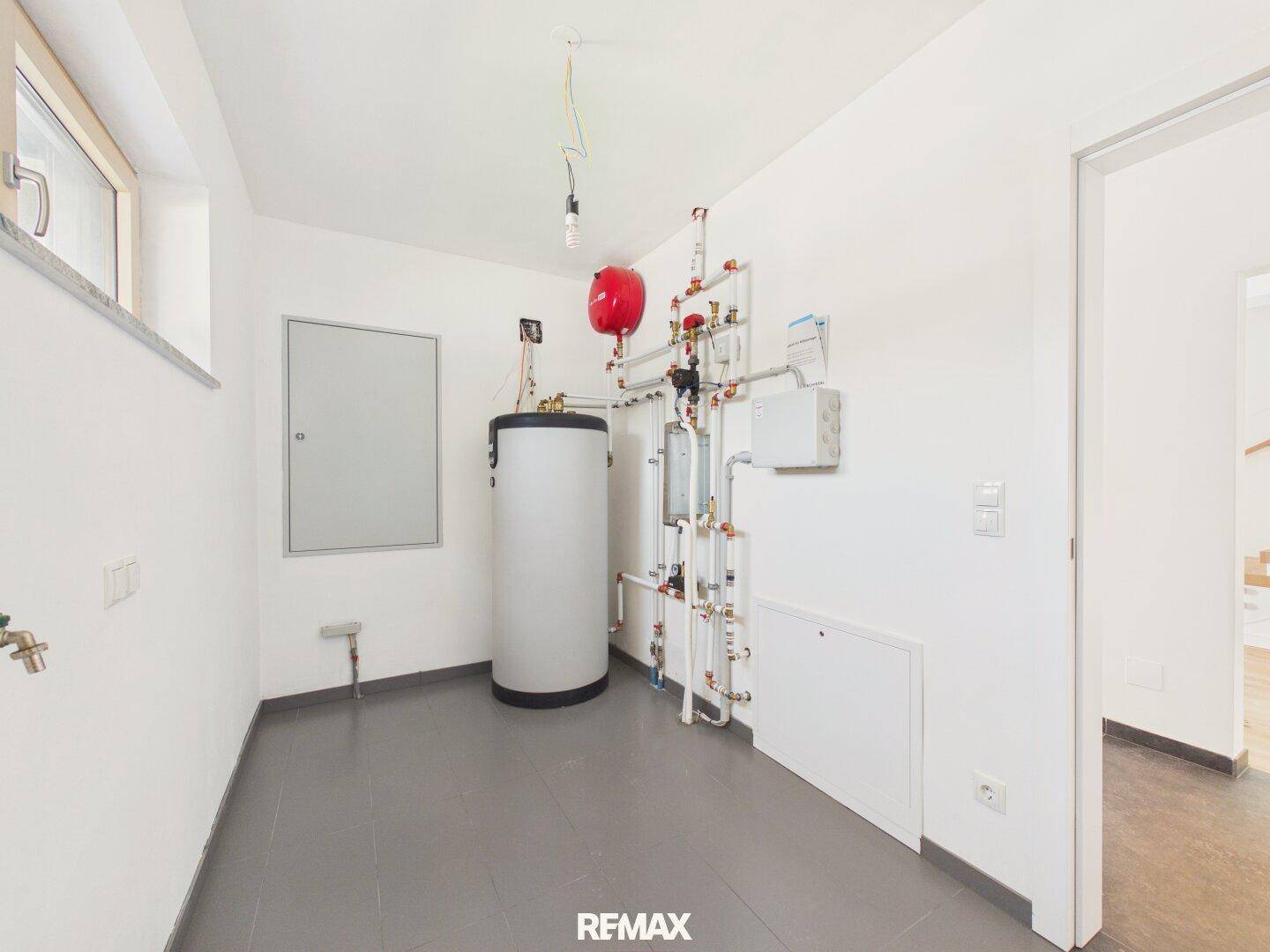 Funktionaler Hauswirtschaftsraum mit Warmwasserspeicher und sichtbaren Installationen.