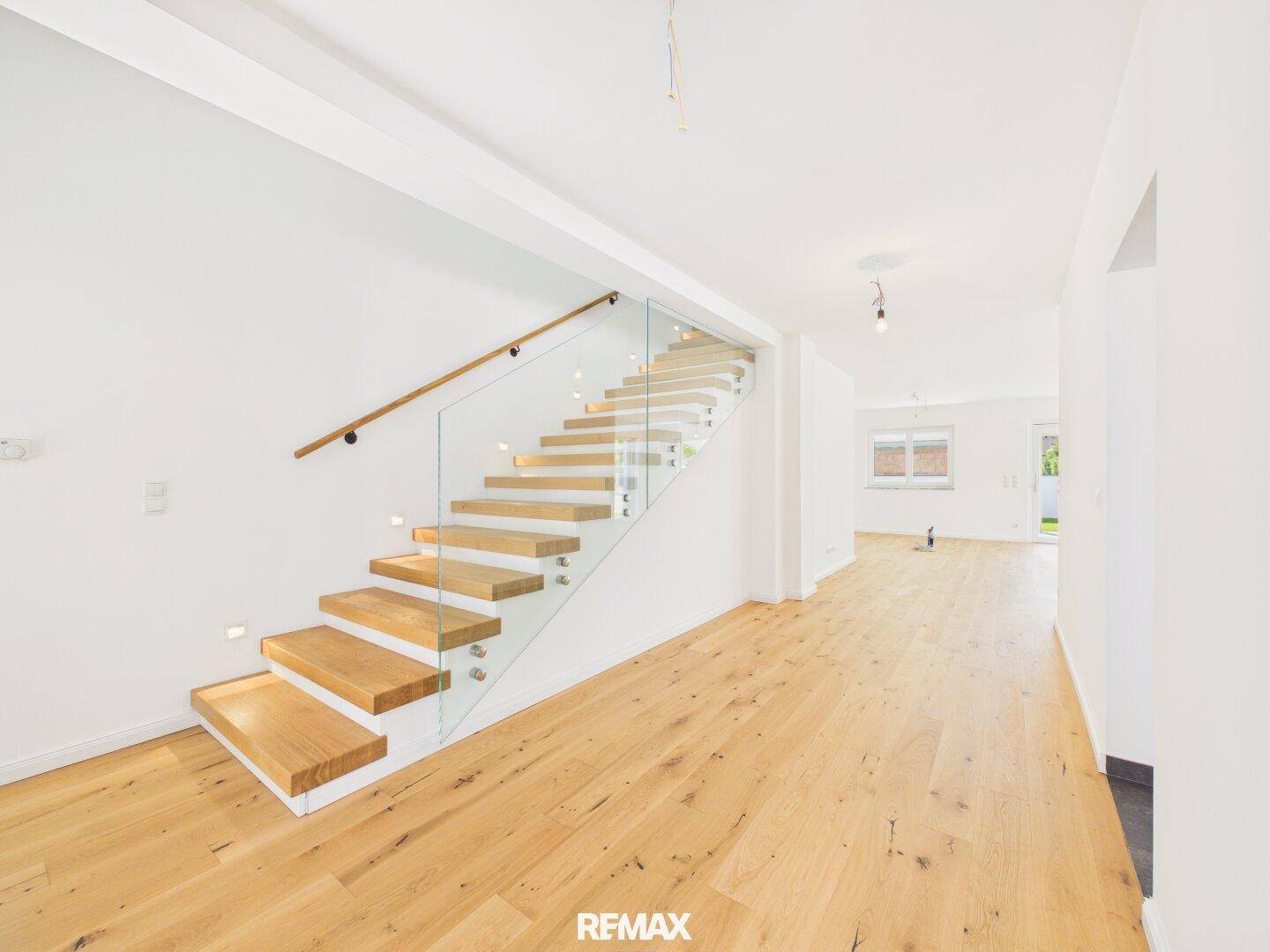 Heller Eingangsbereich mit moderner Holztreppe, Glasgeländer und Eichenparkettboden.