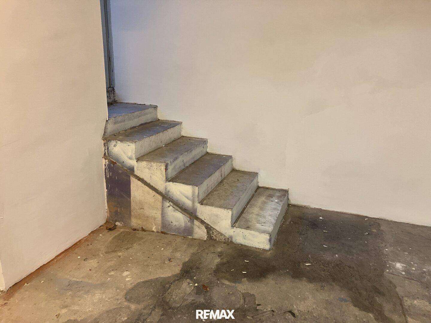 Robuste Betontreppe, die von einem Kellerbereich nach oben führt.