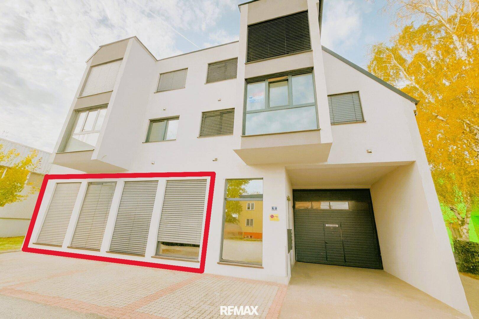 Moderne Gebäudefassade mit großen Fenstern, Rollläden und integrierter Garage.