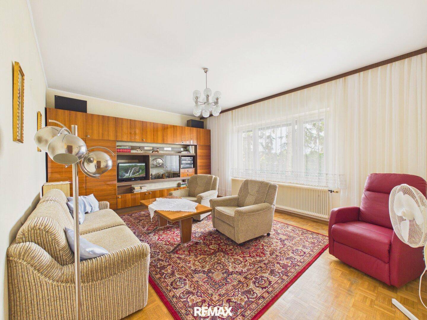 Gemütliches Wohnzimmer im Vintage-Stil mit Teppich, Holzmöbeln und viel Tageslicht.