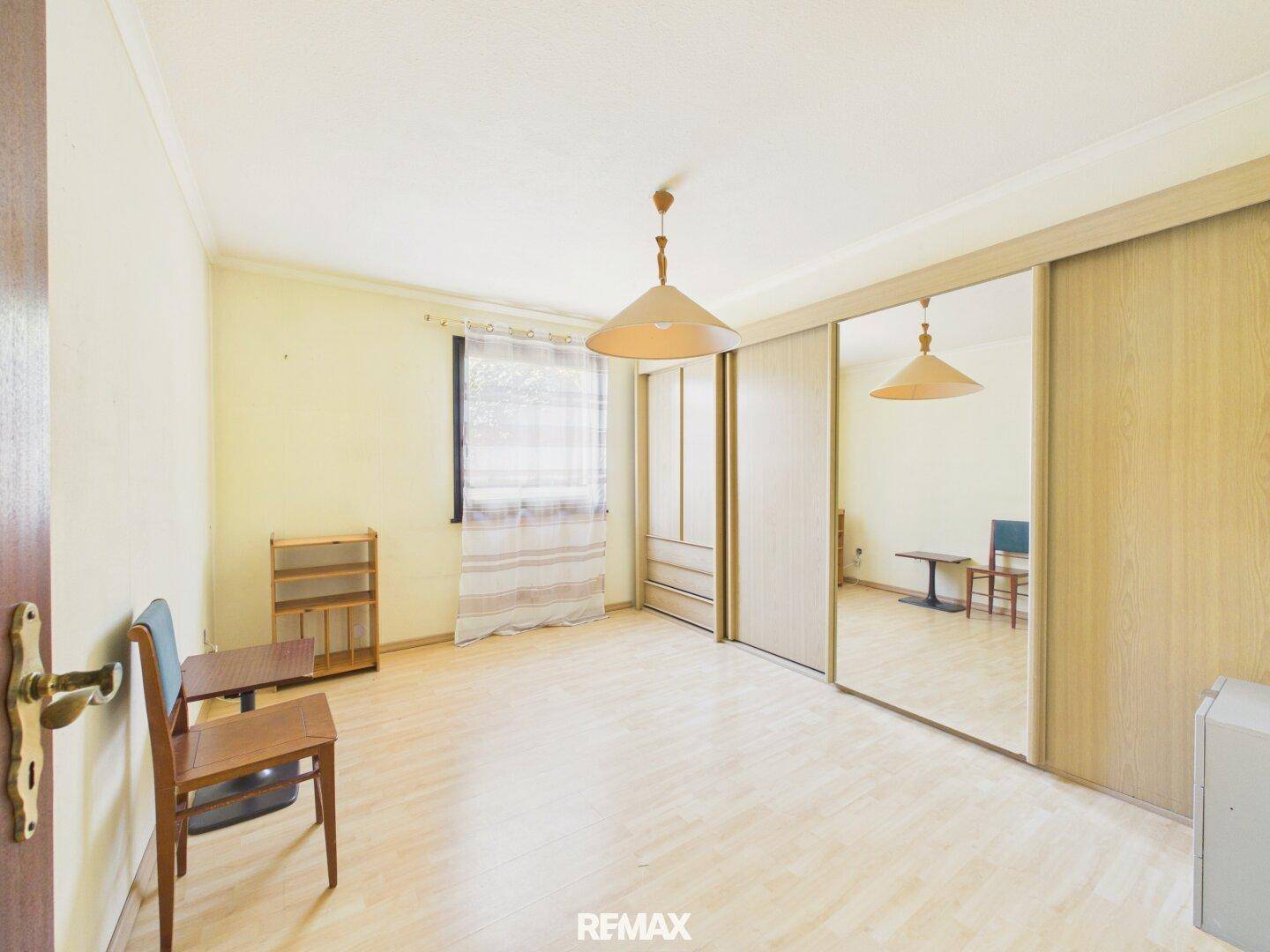 Schlafzimmer mit Laminatboden und großen Spiegelschränken für viel Stauraum.