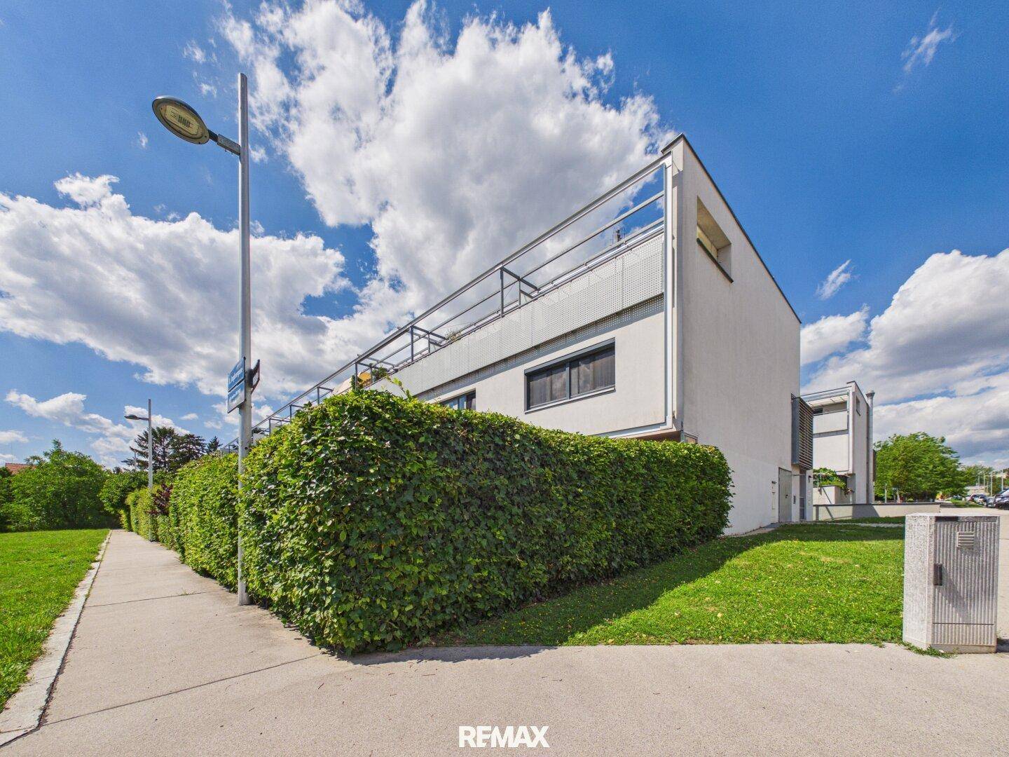 Moderne Architektur des Gebäudes mit klaren Linien und umgebenden Grünflächen unter blauem Himmel.