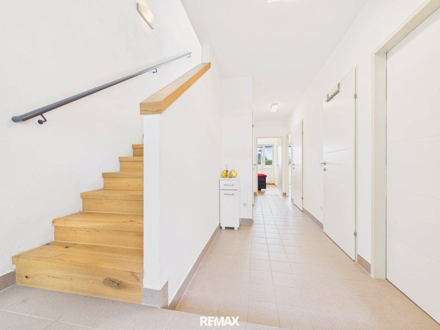 Heller Flur mit Treppe, die in die obere Etage führt, und modernem Fliesenboden.