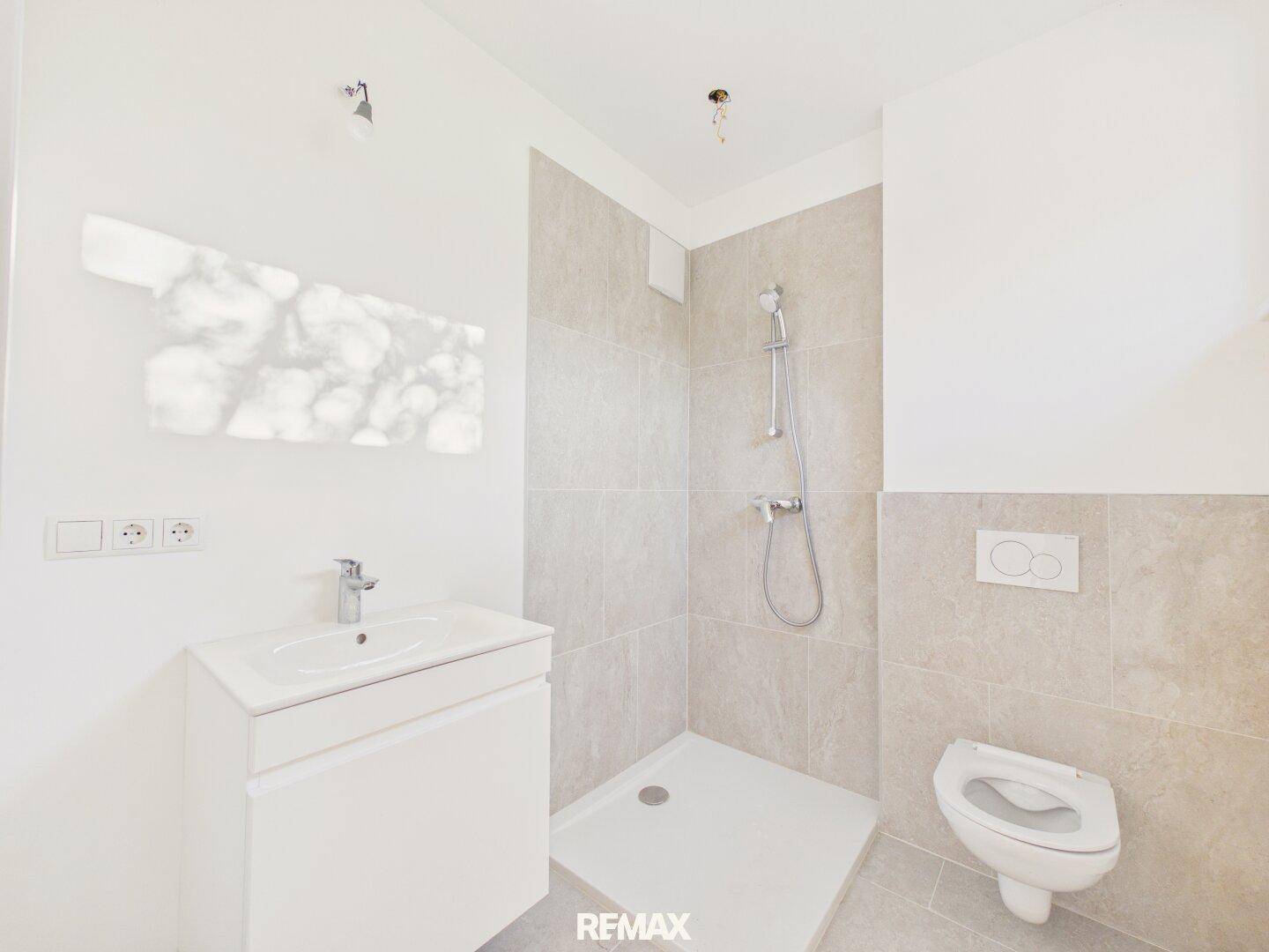 Modernes Badezimmer mit Dusche, WC und Waschbecken, hell gefliest und funktional.