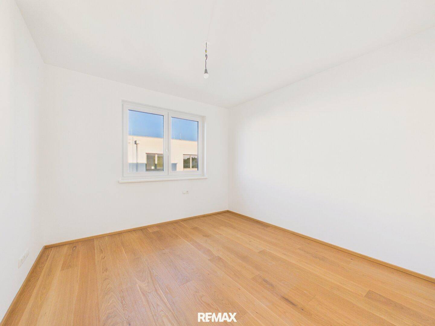 Helles Schlafzimmer mit Holzboden und großem Fenster, bietet viel Tageslicht.