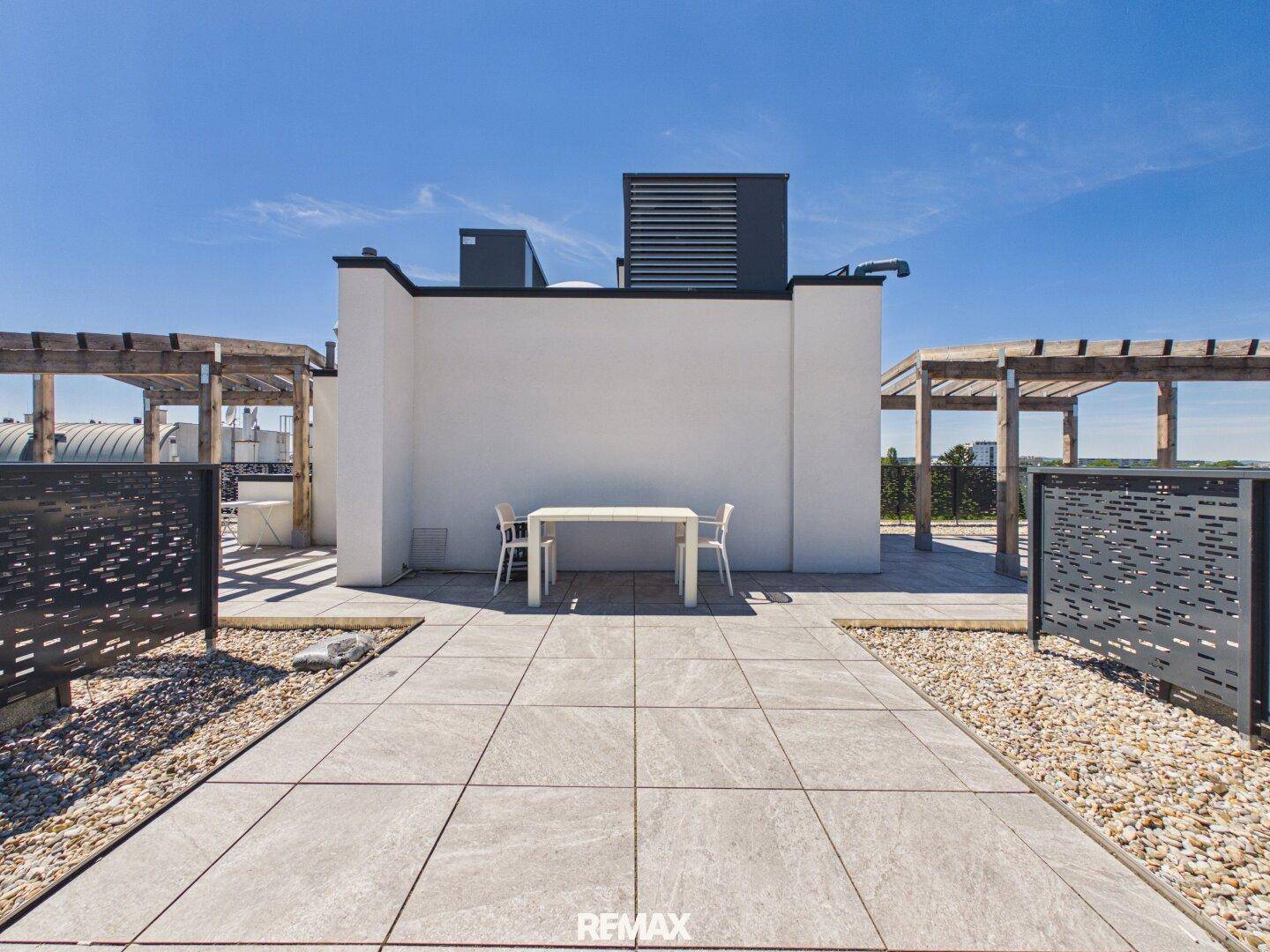 Geräumige Dachterrasse mit Fliesenboden, Sitzgelegenheiten und Holzpergolen.