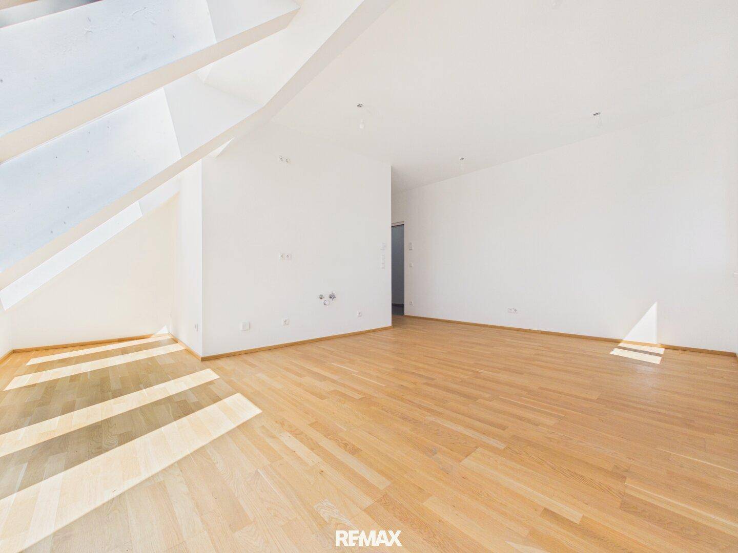 Leerer Raum mit Holzboden, weißen Wänden und einer offenen Treppe.