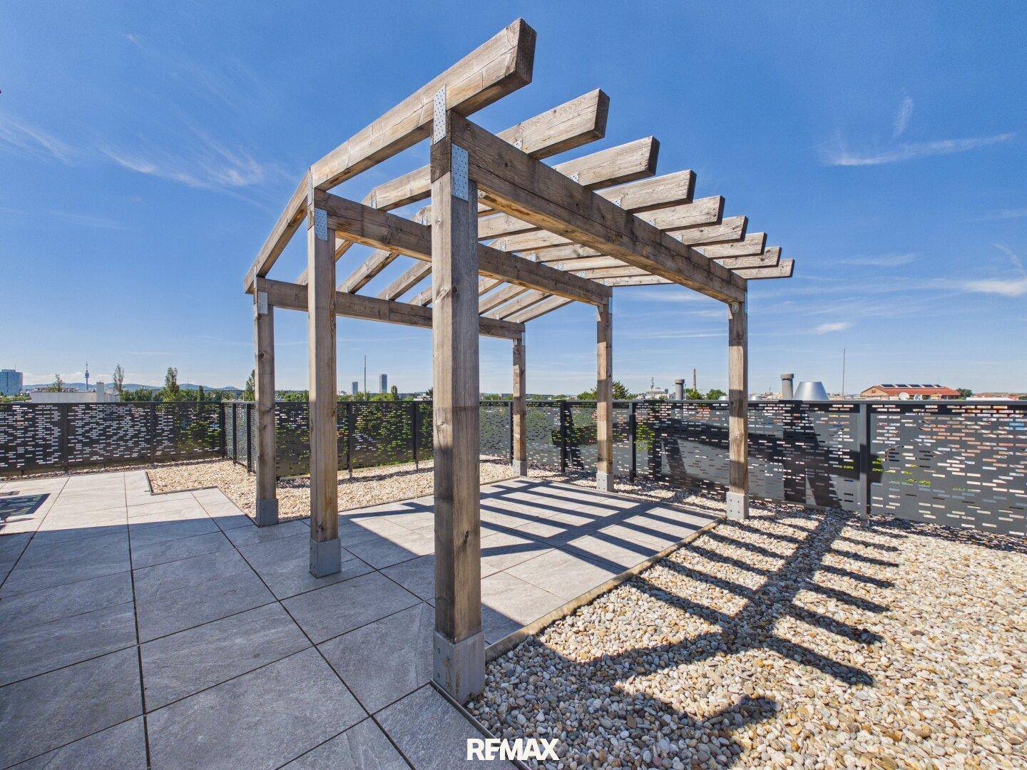 Geräumige Dachterrasse mit großer Holzpergola und Fliesenboden.