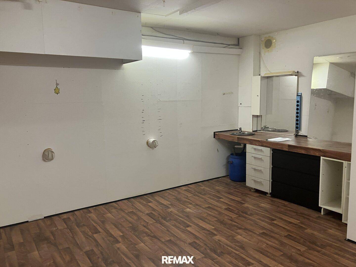 Funktionaler Hauswirtschaftsraum mit Arbeitsplatte, Spülbecken und Laminatboden im Untergeschoss.