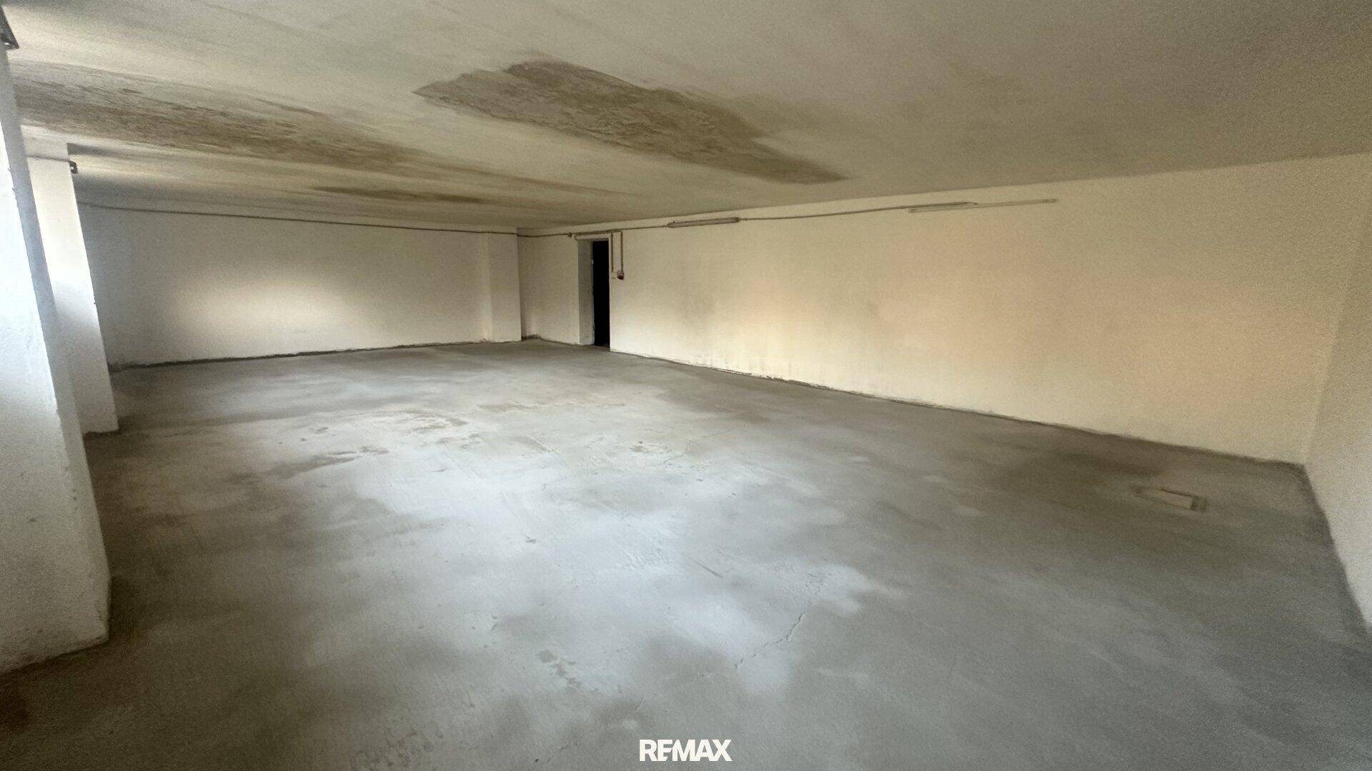 Großer, leerer Kellerraum mit Betonboden und weiß gestrichenen Wänden, ideal als Lagerfläche.
