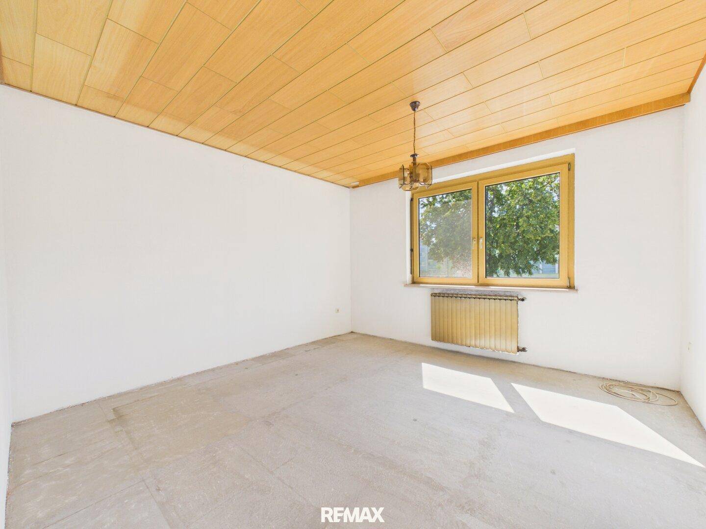 Heller Raum mit Holzpaneeldecke und großem Fenster, ideal für individuelle Gestaltung.