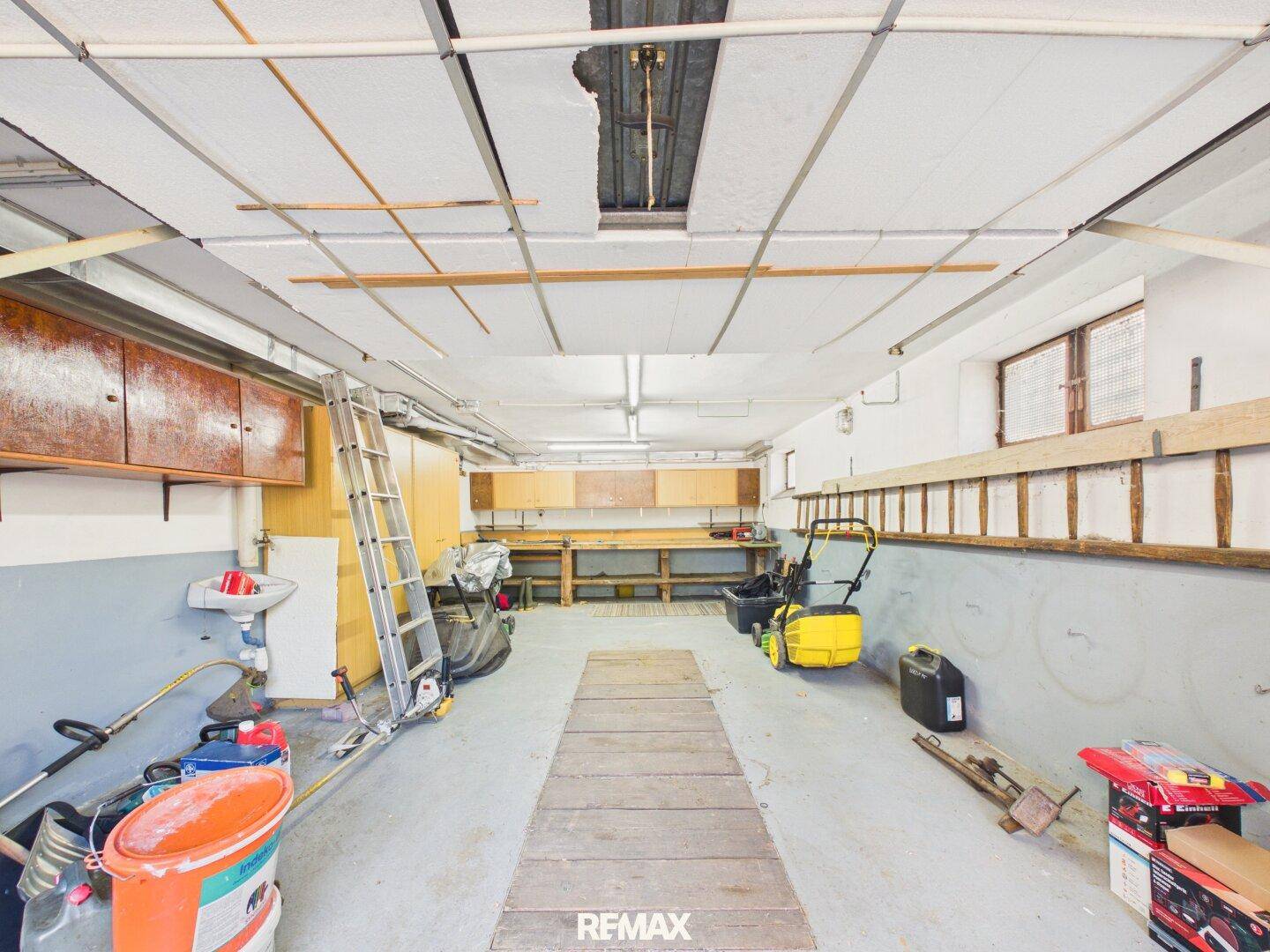 Geräumige Werkstatt oder Garage mit Arbeitsflächen, Regalen und Werkzeugen.