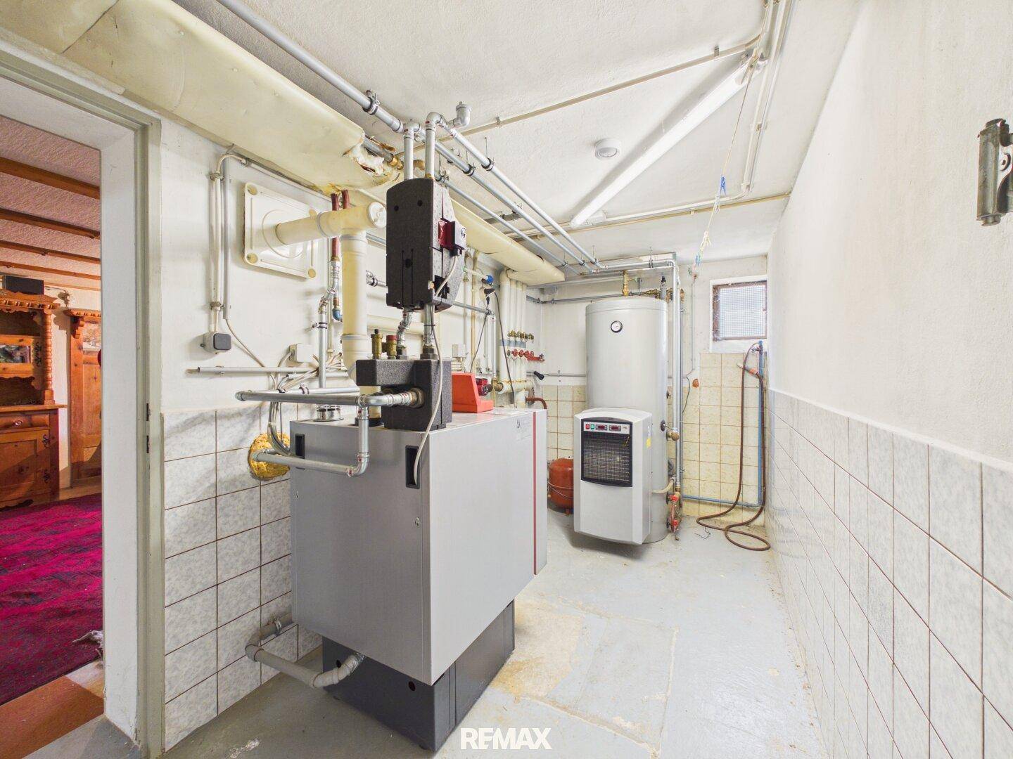 Heizungsraum im Keller mit moderner Heizungsanlage und Warmwasserspeicher.