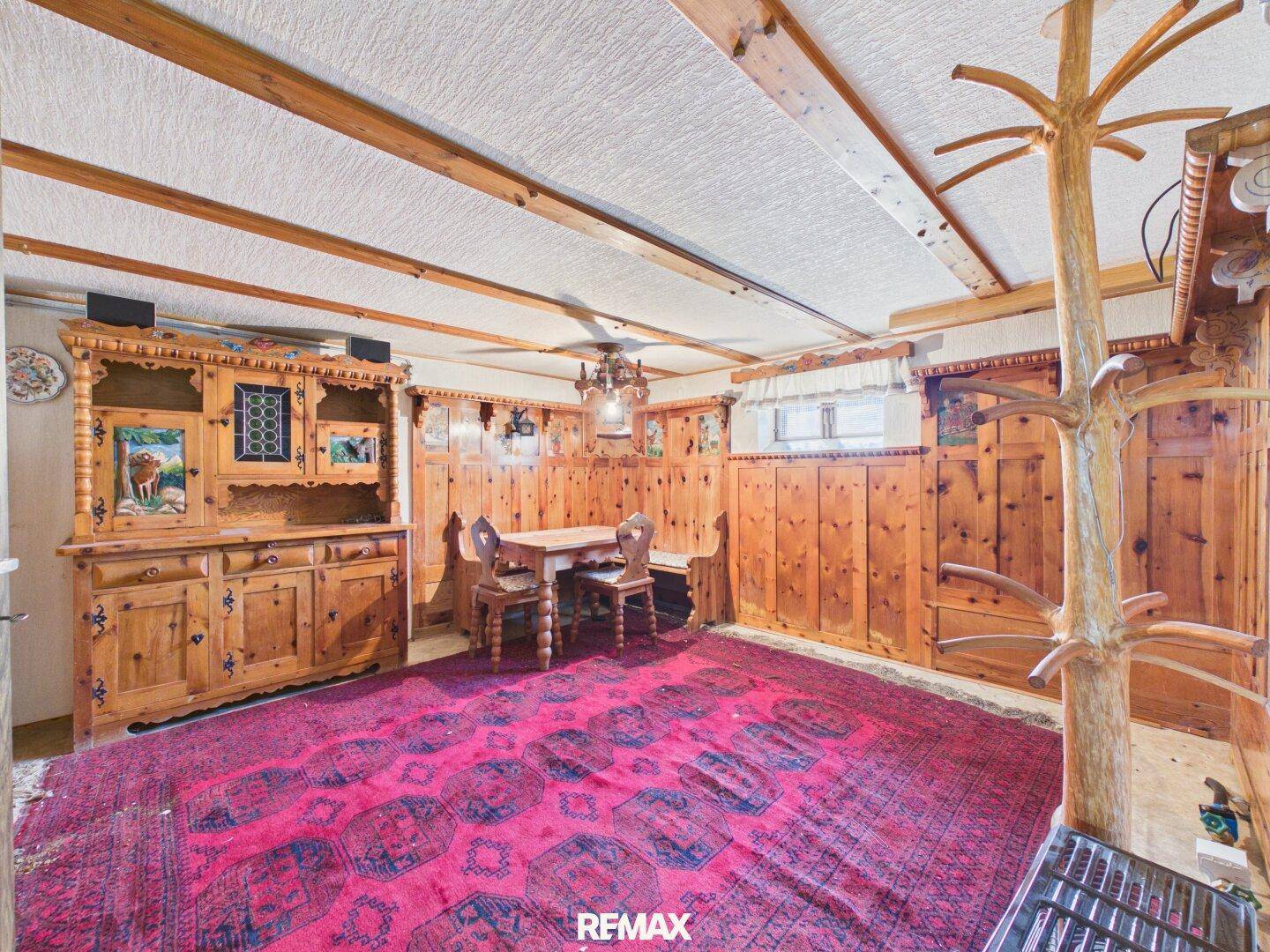 Rustikaler Wohnraum im alpinen Stil mit Holztäfelung, Teppich und traditionellen Möbeln.